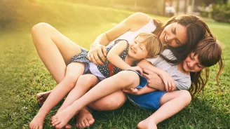 Mother playing with her children on the lawn.