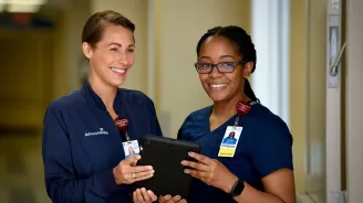 Two nurses from AdventHealth holding a tablet