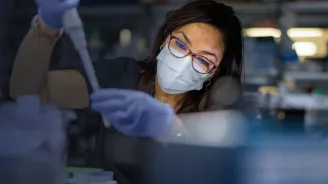 Masked Woman in Lab holding a syringe