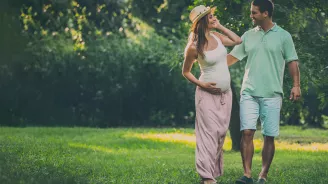 A pregnant woman walking outdoors with her husband.