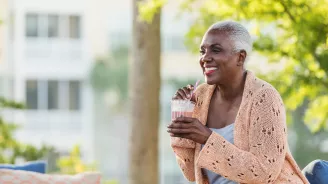 A Black Woman Enjoys a Smoothie on a Bench Outside