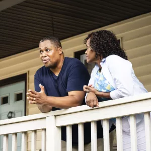 A middle-aged couple standing on the porch together