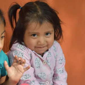 A Guatemalan girl tries stifle a smile when looking into the camera.