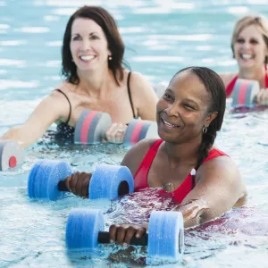 Three women building knee strength in a water aerobics class.