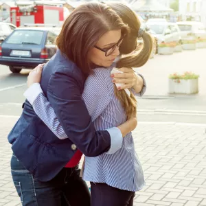 Two women comfort each other with a hug.