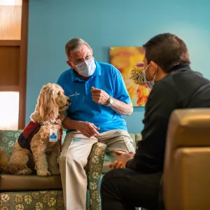 An AdventHealth employee with a service dog and talking to a patient