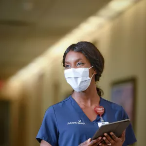 An AdventHealth nurse walking down the hallway with her tablet