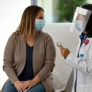 A doctor examines a patient wearing personal protective equipment.