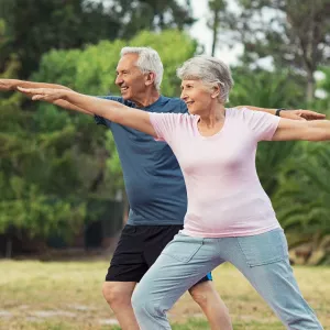 A happy older couple stretching outdoors.