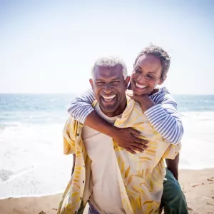 An older couple smiling while at the beach.