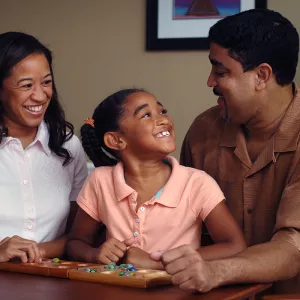 A daughter smiles at her father while playing a game with her parents. 