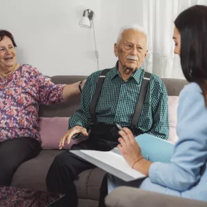 caregiver with eldery couple at home 