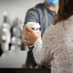 Foxtail barista handing a woman a cup of coffee.