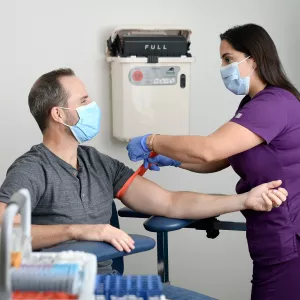 Lab technician preparing man for a blood draw.