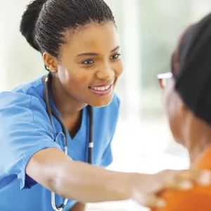 A nurse placing her hand on her patient's shoulder