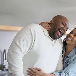 A couple hugging each other while cooking on the kitchen