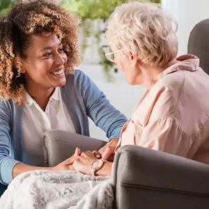 A caregiver helps an elderly patient in their home.