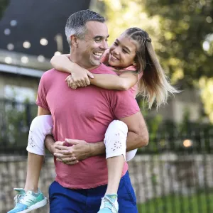 A dad giving his daughter a piggyback ride.