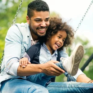 A dad swings with his giggling child.