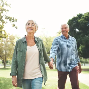 Elderly couple holding hands and walking in a park