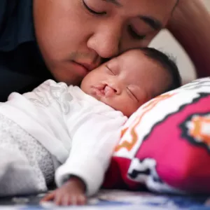 A father cuddling his infant.