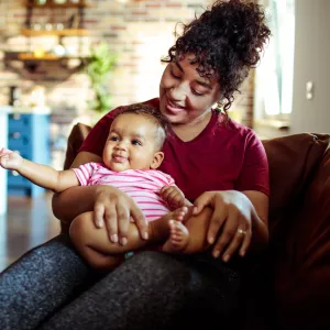 A mother and her infant sitting on the couch at home.