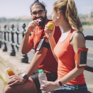 Two runners eat a healthy snack.