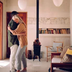 A mature man and woman embrace in their living room