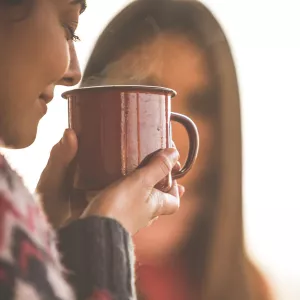 A woman smelling a fresh cup of her tea