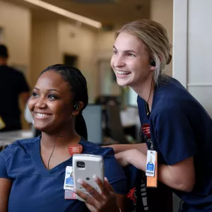 Two nurses from AdventHealth, smiling and looking to the left. 