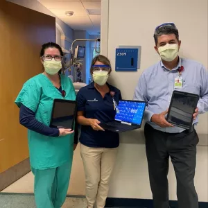 AdventHealth Palm Coast team members Jennifer Mellow, Wendi Coheley and Eddie Conclaves with the tablets used to host a patient's virtual anointing ceremony.