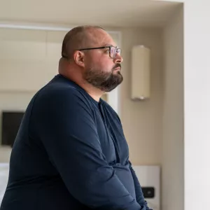 A man sitting at home looking onward.