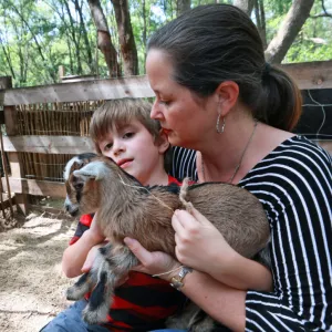 Cameron Munoz and one of her sons snuggle a baby goat at Puzzle Ranch in Sorrento, Florida.