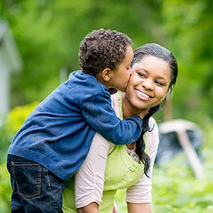 Son kissing his mother while they're outdoors.