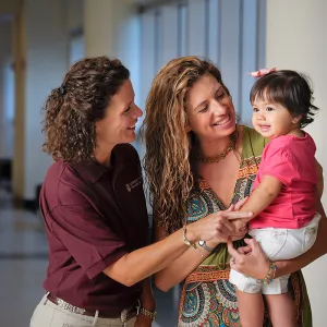 Two woman holding a child.