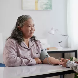 Adult daughter checking senior mother's blood pressure.