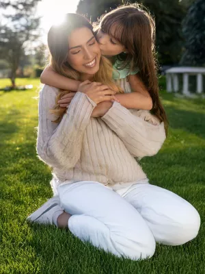 Mother and daughter embracing in yard