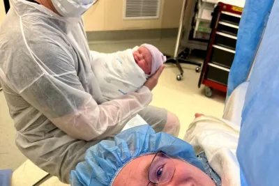 Meredith in her C-Section with her husband holding their newborn baby