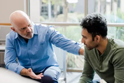 A Therapist Speaks to His Patient and Put's his Hand on His Shoulder