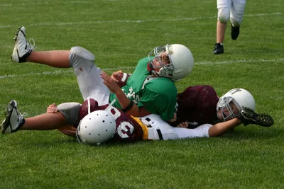 A Teen in Football Pads Getting Tackled