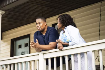 A middle-aged couple standing on the porch together