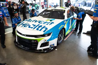 AdventHealth racing car in garage with pit crew surrounding it 