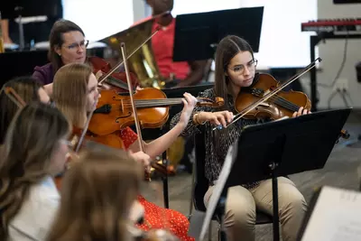 Ivanna Mirabal Molina, right, rehearses with the AdventHealth employee orchestra.