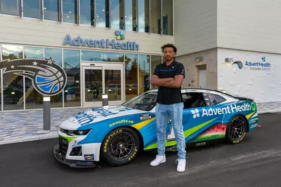 Orlando Magic player, Wendell Carter Jr. poses in front of the AdventHealth NASCAR vehicle at the AdventHealth Training Center