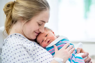 A smiling woman holding her newborn baby.