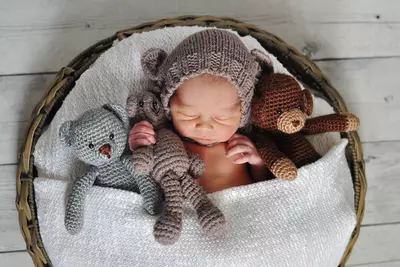 baby sleeping in basket with stuffed animals