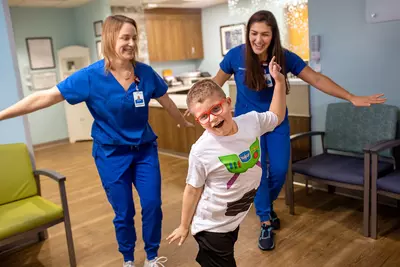 A boy wearing a buzz lightyear shirt with two AdventHealth employees.