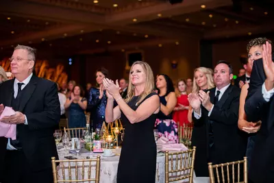 A group of people clapping at a gala night.