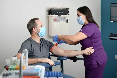 Lab technician preparing man for a blood draw.