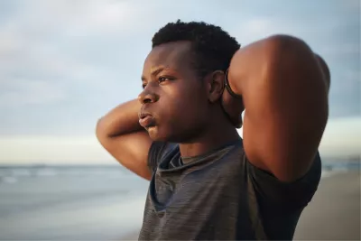 A teenage boy with a frustrated expression looks out over the ocean.